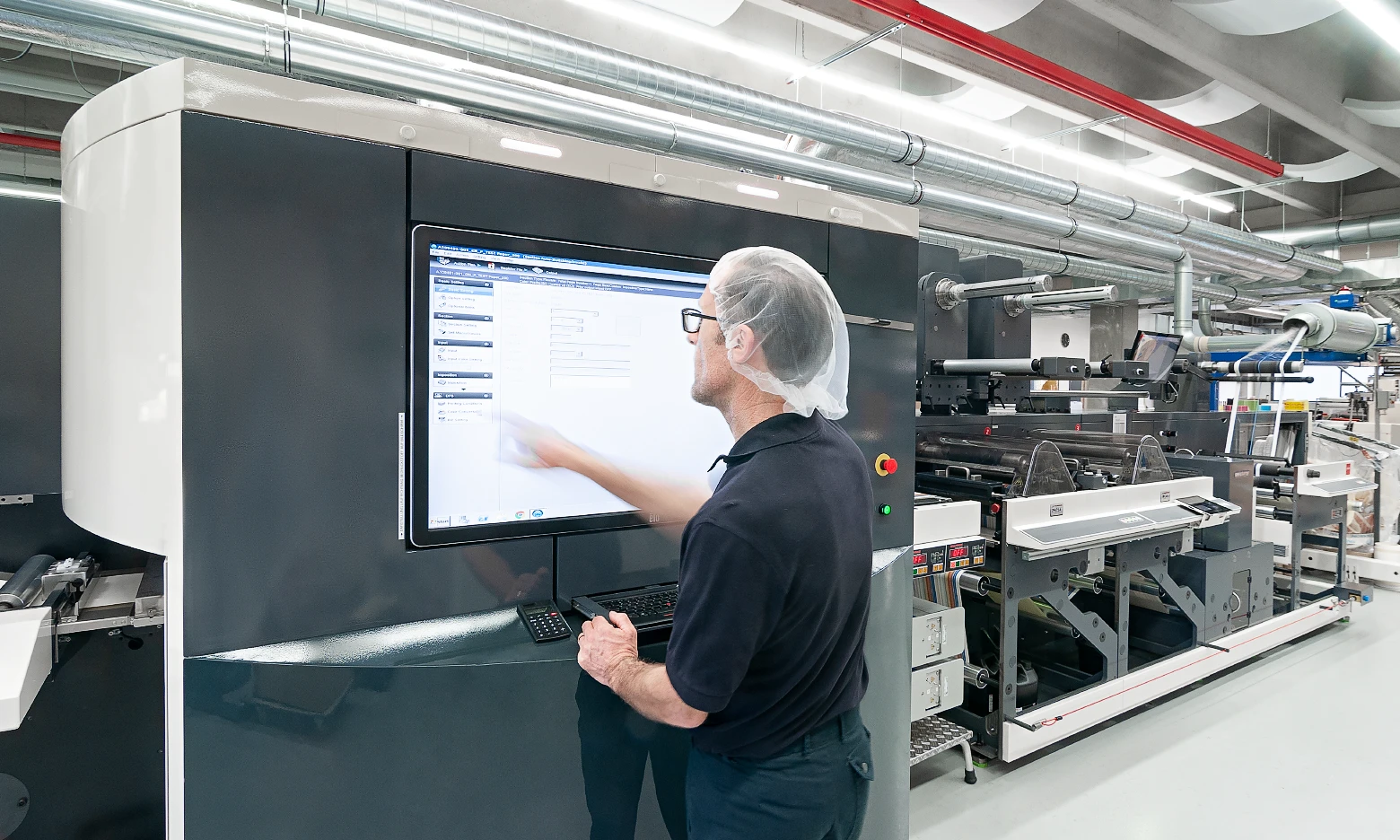 Employee operating a printing press for pharmaceutical label production